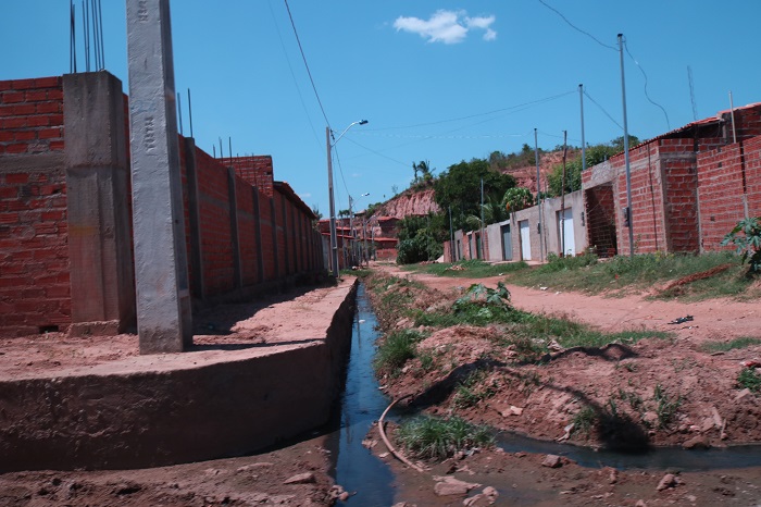 Rua sem pavimentação e com esgoto a céu aberto