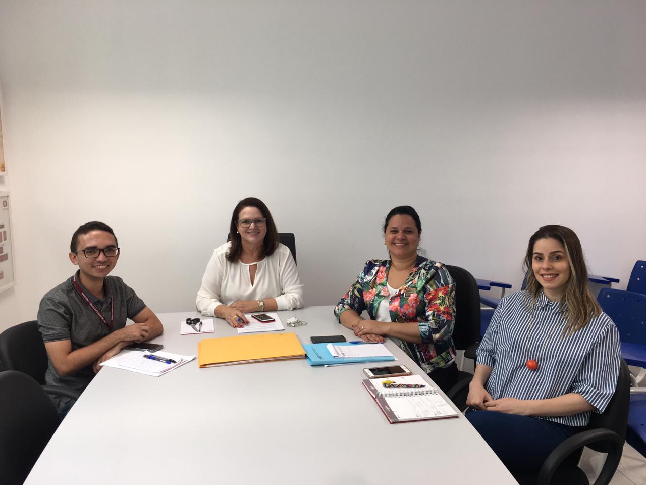 Pessoas sentadas envolta de uma mesa 