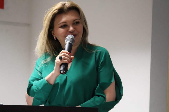 Mulher falando diante de plateia 