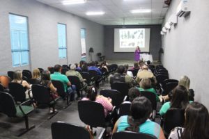 Pessoas sentadas em auditório assistindo palestras