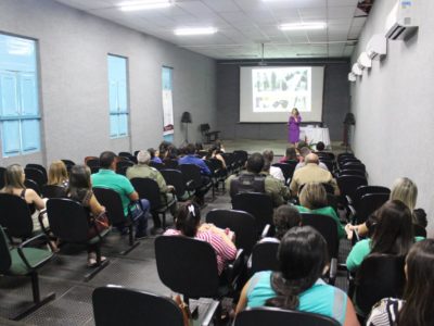 Pessoas sentadas em auditório assistindo palestras