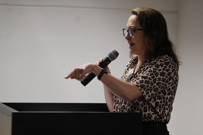 Mulher falando para plateia de auditório 