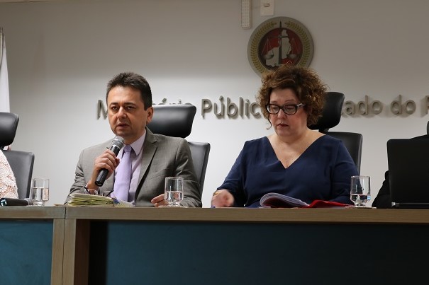 Um homem e uma mulher sentados à mesa de frente para o público