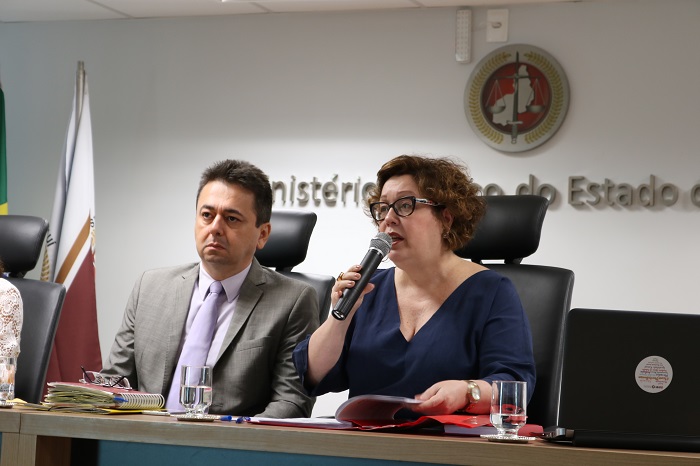 Um homem e uma mulher sentados à mesa de frente para o público