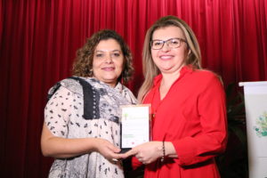 PGJ Carmelina Moura recebe das mãos da Superintendente da SASC, Janaína Mapurunga, a homenagem.
