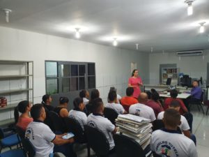 Mulher em pé falando para pessoas sentadas
