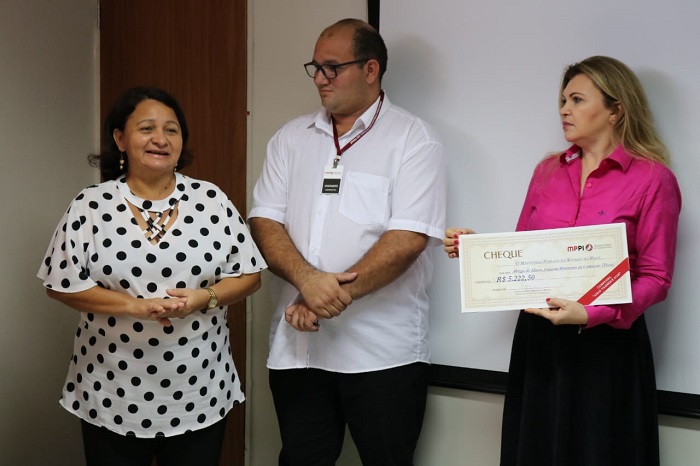 Pessoas reunidas para foto segurando cheque