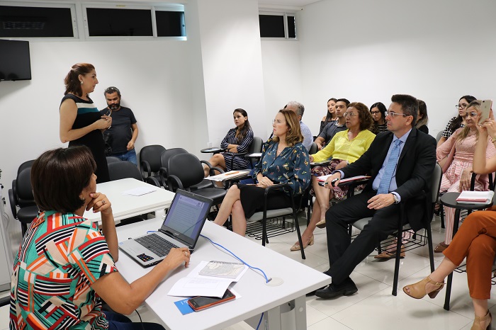 Mulher em pé falando ao público sentado