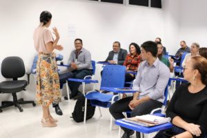 Mulher em pé falando para pessoas sentadas