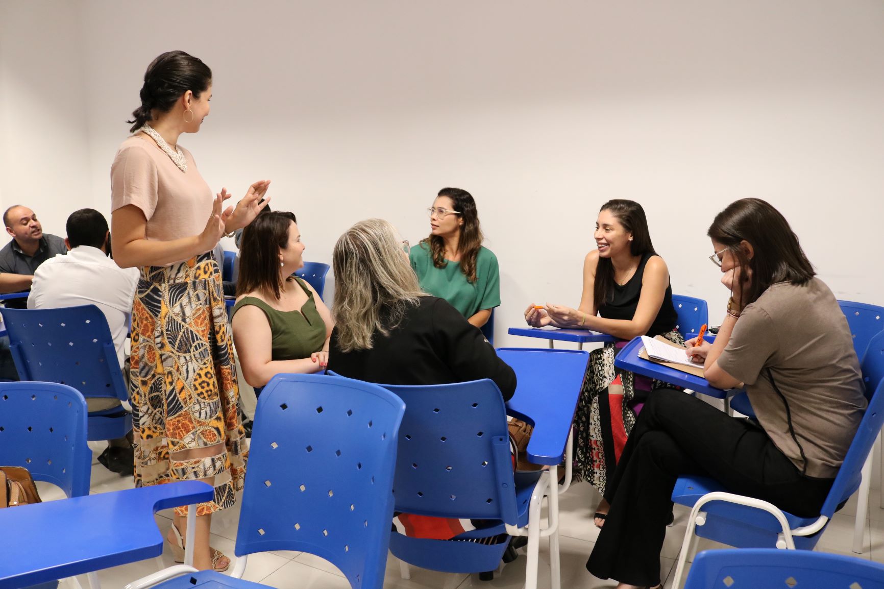 Mulher em pé conversando com mulheres sentadas