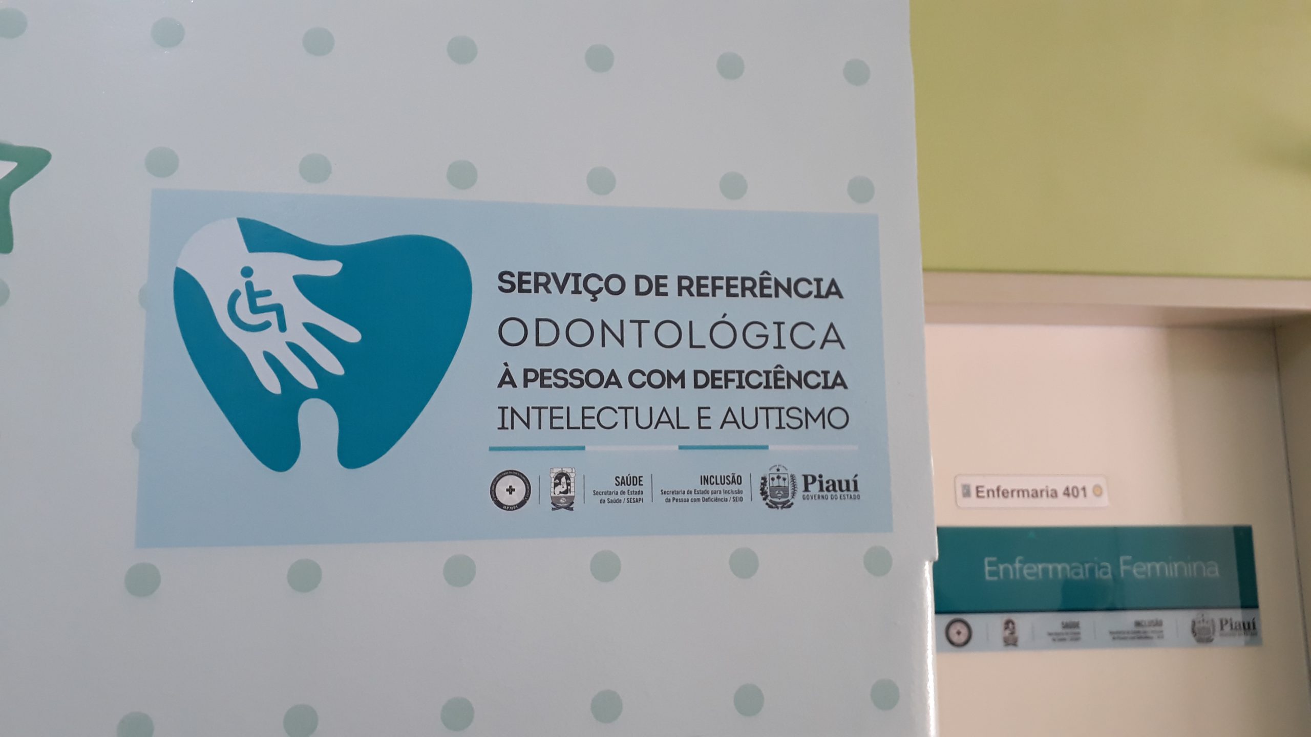 Parede com adesivo sinalizando o Serviço de Referência Odontológica à Pessoa com Deficiência Intelectual e Autismo