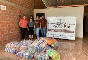 Pessoas de pé em frente aos alimento obtidos com a arrecadação