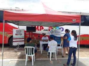 Pessoas sentadas em tenda recebendo atendimento