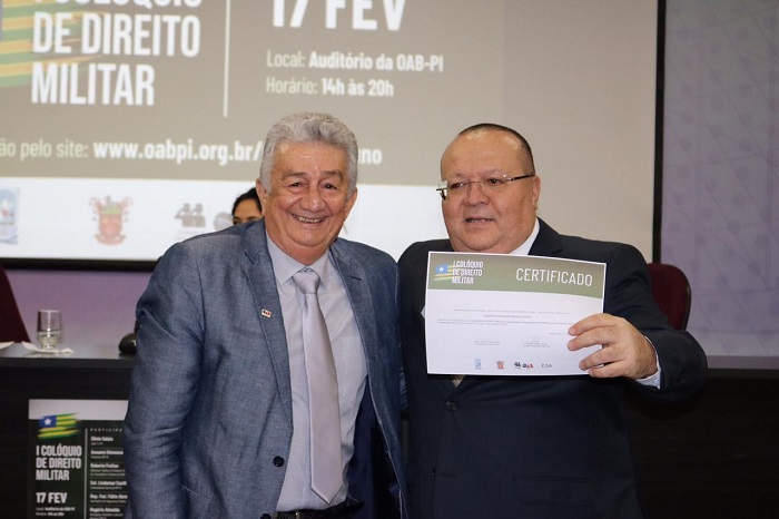 Homem segurando certificado ao lado de palestrante 