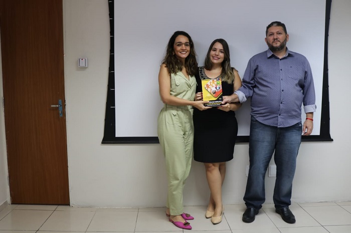 Pessoas posando para foto segurando livro