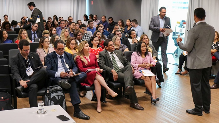 Pessoas sentadas em auditório assistindo palestra 