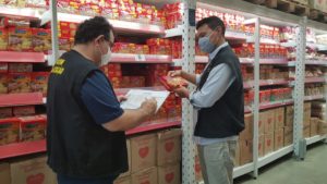 Duas pessoas de pé verificando preço de um produto alimentício