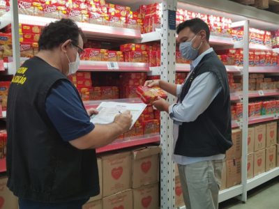 Duas pessoas de pé verificando preço de um produto alimentício