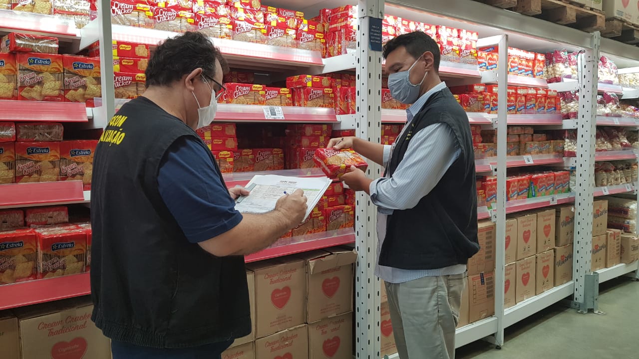 Duas pessoas de pé verificando preço de um produto alimentício