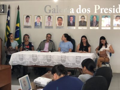 Pessoas sentadas atrás de uma mesa durante audiência pública