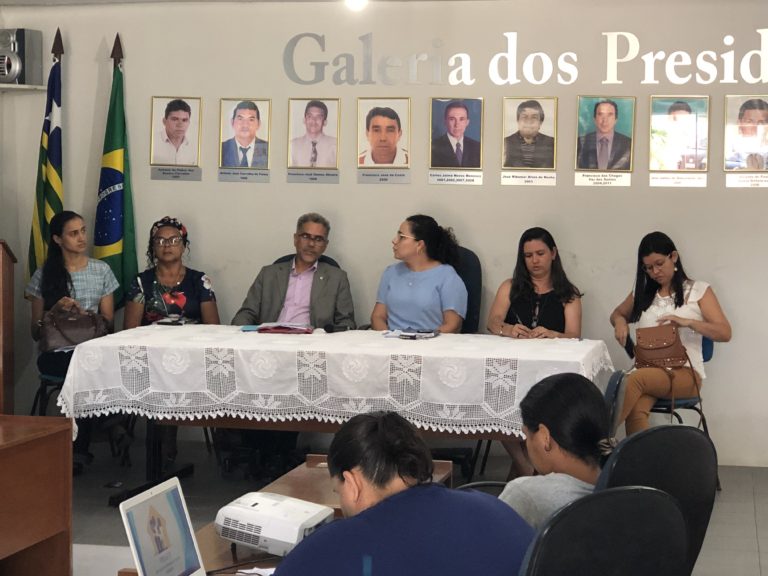Pessoas sentadas atrás de uma mesa durante audiência pública