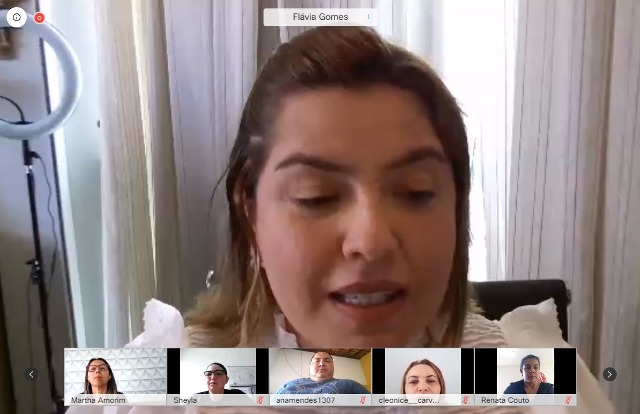 Promotora de Justiça Flávia Gomes durante reunião virtual. Na parte inferior da imagem, pessoas observam a fala dela
