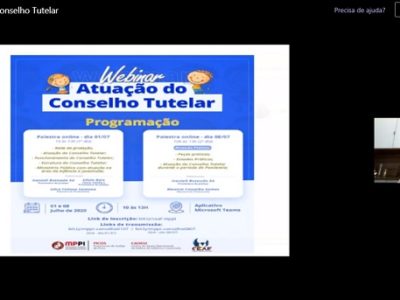 Imagem de uma pessoa ministrando palestra. Ao lado dessa pessoa há uma tela com uma apresentação sobre o assunto que está sendo discutido na palestra.