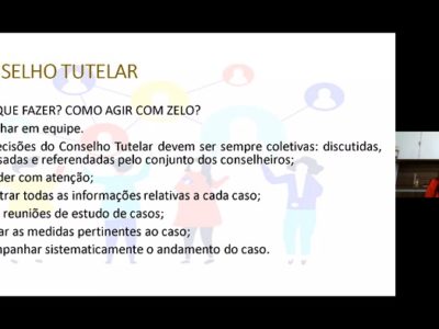 Imagem de uma pessoa falando. Ao lado dessa pessoa apareece uma tela com a projeção de um conteúdo.